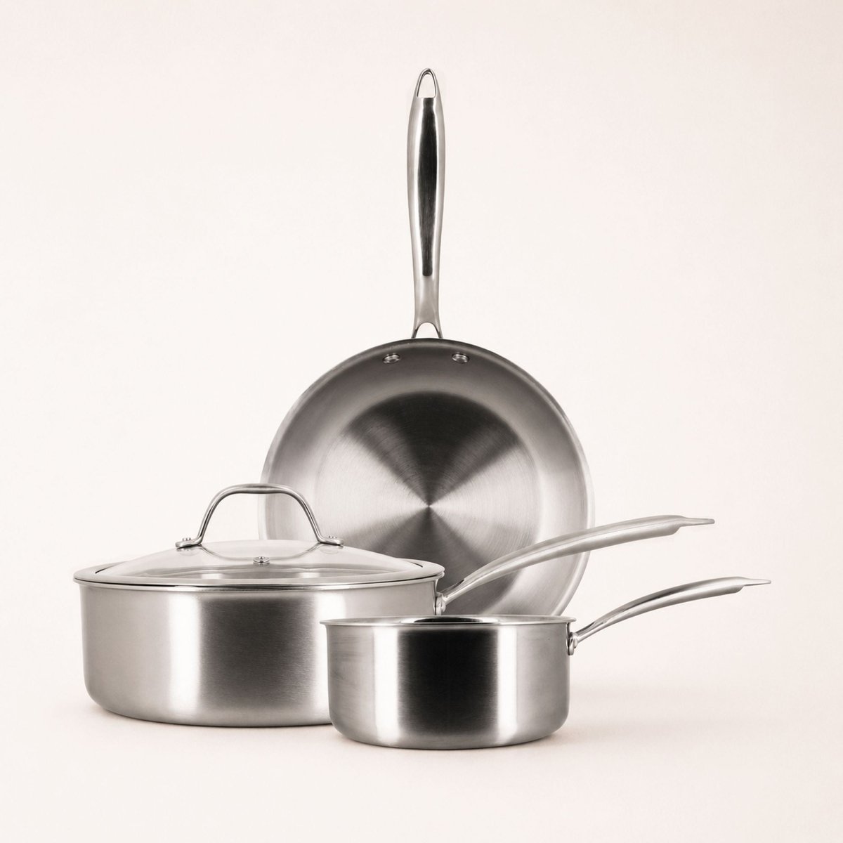 Set de 3 pièces Triply Menastyl en acier inoxydable : poêle, casserole et sauteuse empilées sur fond clair