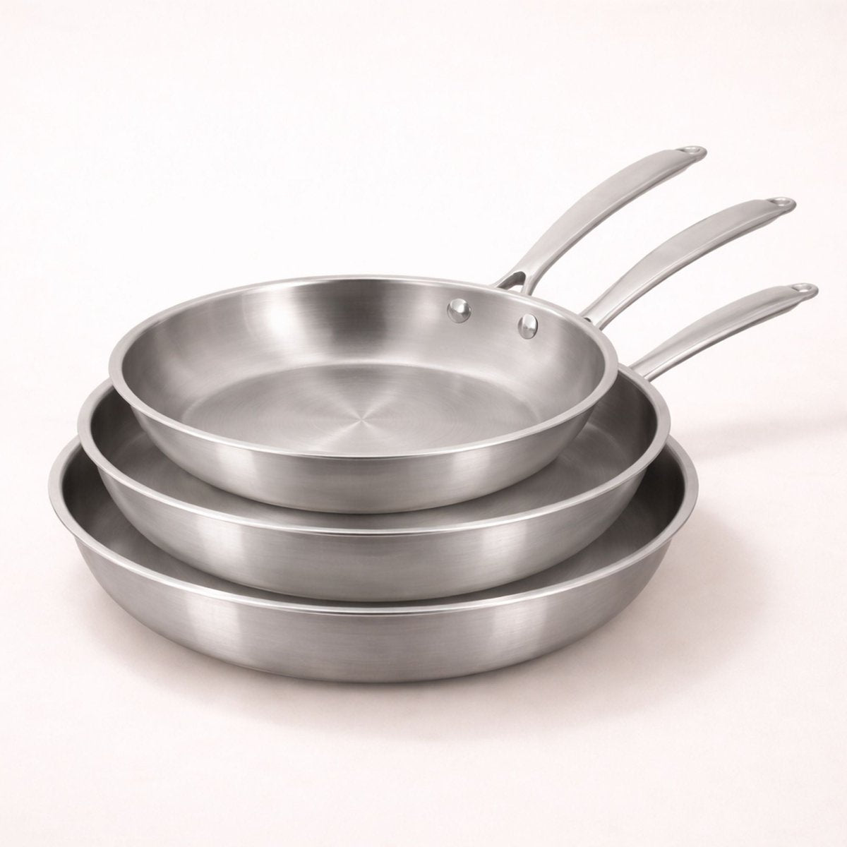 Set de 3 poêles Triply Menastyl en acier inoxydable empilées 20, 24 et 28 cm, vue d'ensemble sur fond clair