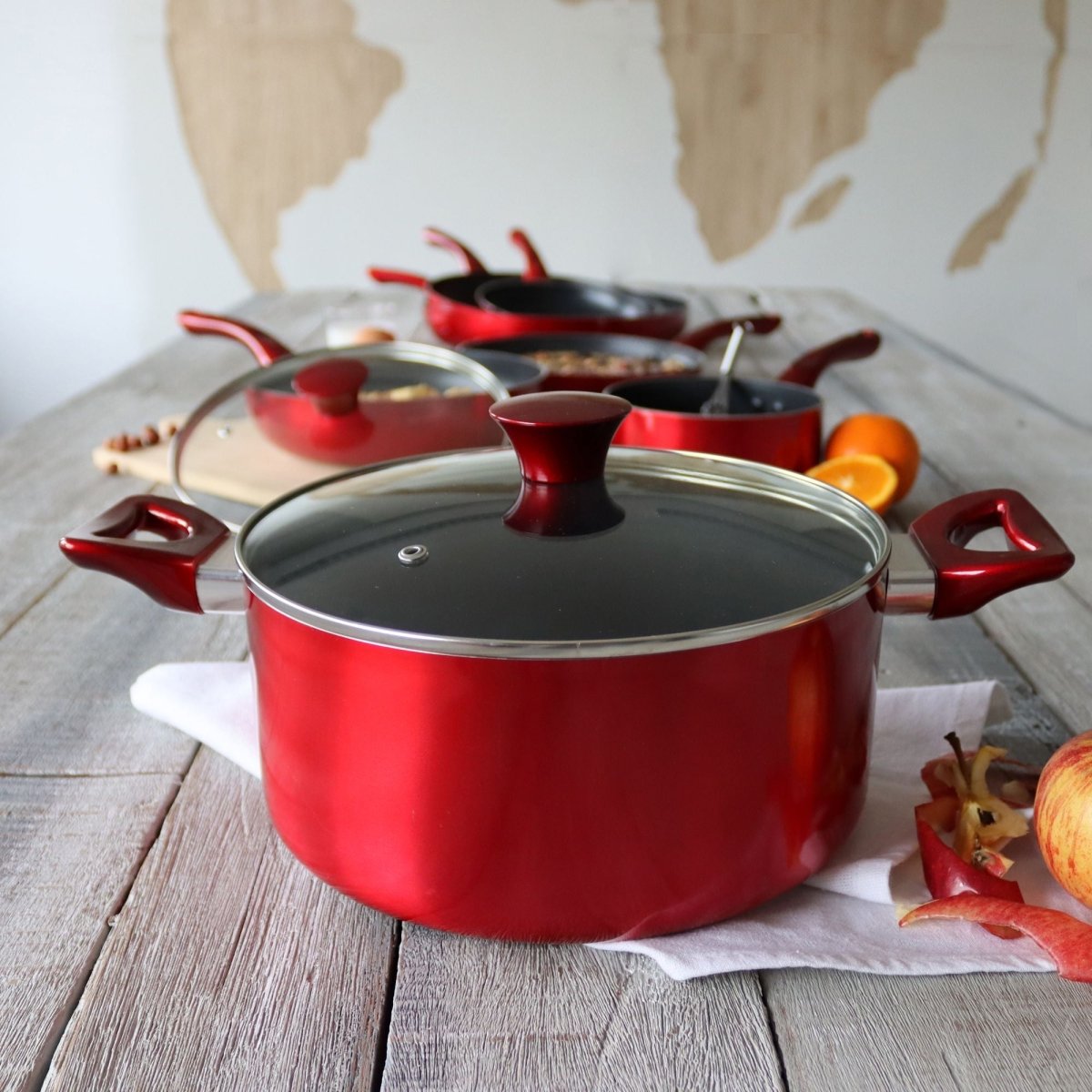Set de 5 pièces Cerise rouge métallisé disposé sur table en bois clair, faitout avec couvercle au premier plan