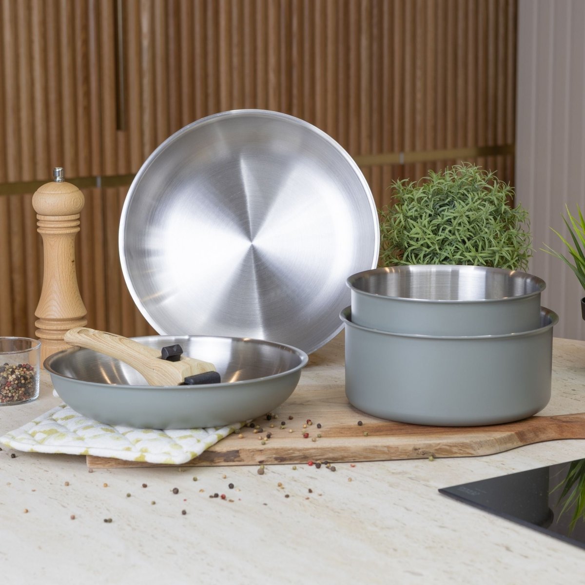 Set de 5 casseroles et poêles Easynox empilées, finition inox et gris, avec spatule en bois sur plan de travail