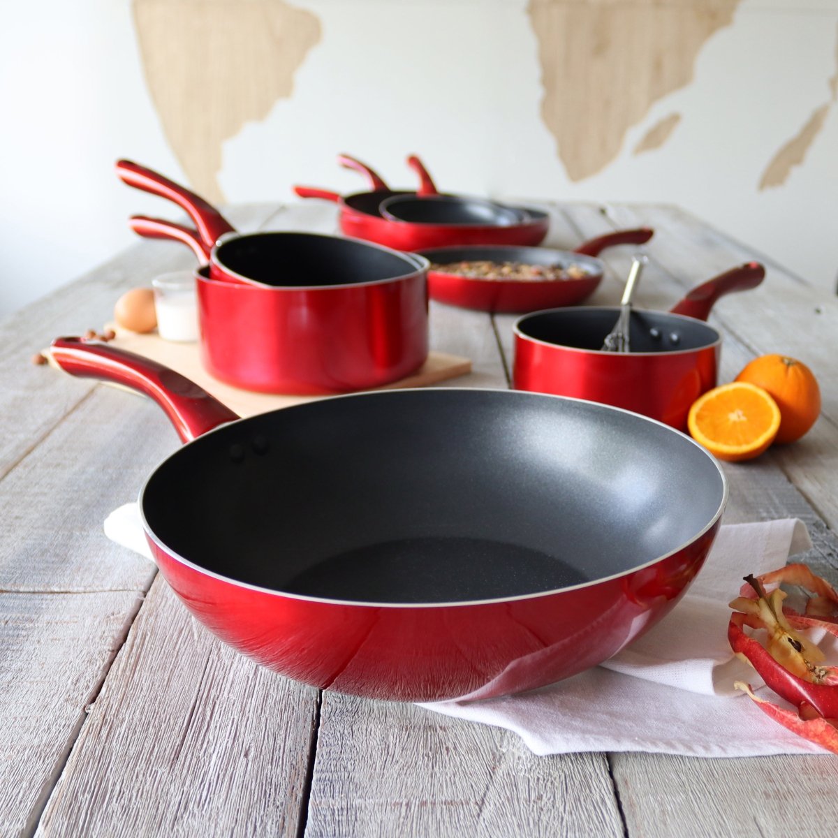 Set 7 pièces Cerise en aluminium rouge et noir disposé sur table en bois avec ustensiles de cuisine