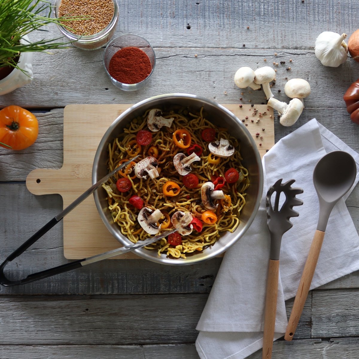 Casserole acier inoxydable Iris avec plat de nouilles, champignons et poivrons sur table en bois rustique