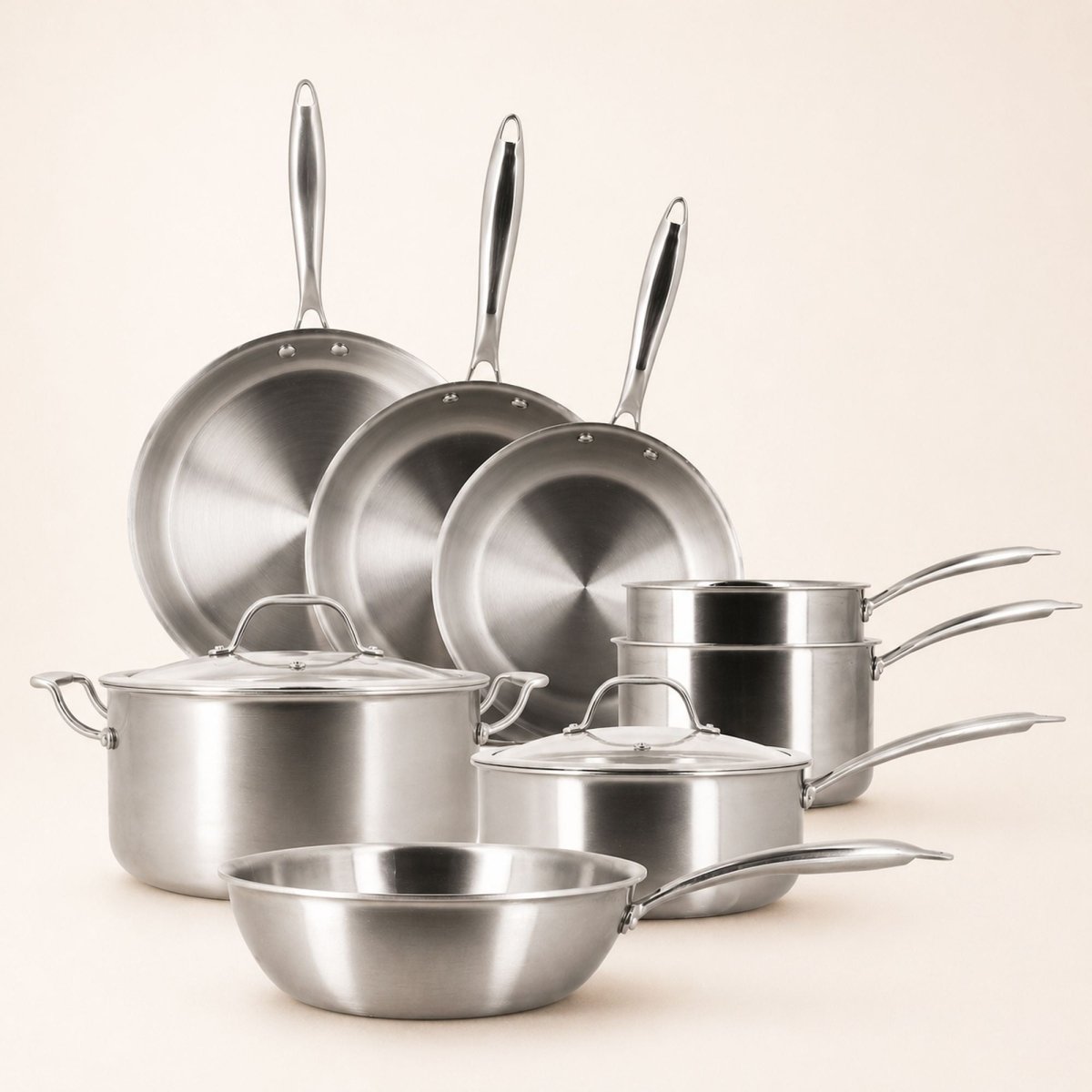 Set de 8 pièces Triply Menastyl en acier inoxydable : poêles, casseroles, faitout et wok empilés sur fond beige