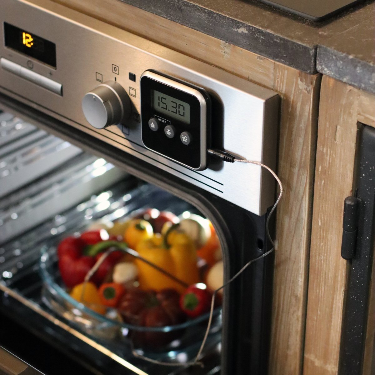 Thermomètre de cuisson Oriane magnétique posé sur four, sonde insérée dans bol de légumes, affichage digital 15:30