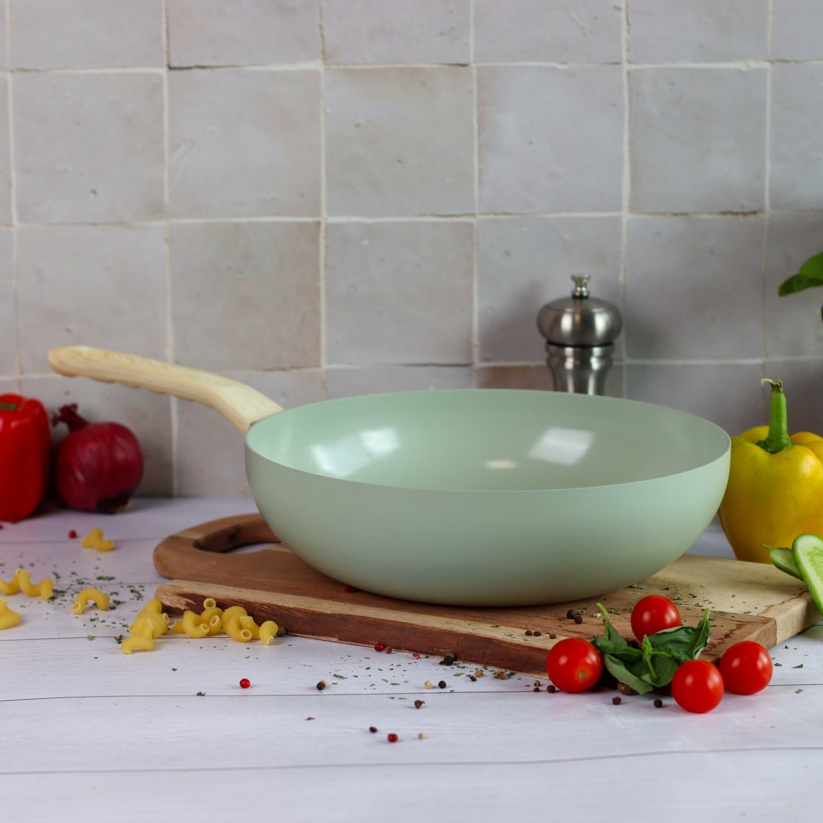Wok Colorama 28 cm vert menthe posé sur planche bois avec légumes et pâtes fraîches