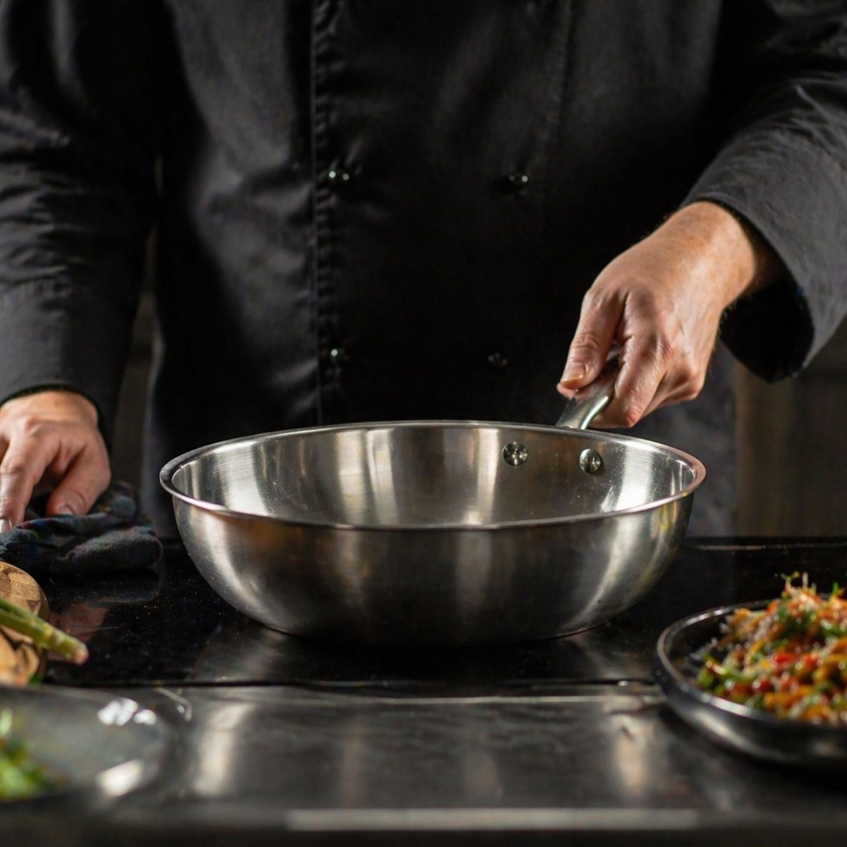 Chef professionnel préparant des ingrédients dans un wok Triply 24cm en acier inoxydable triple couche