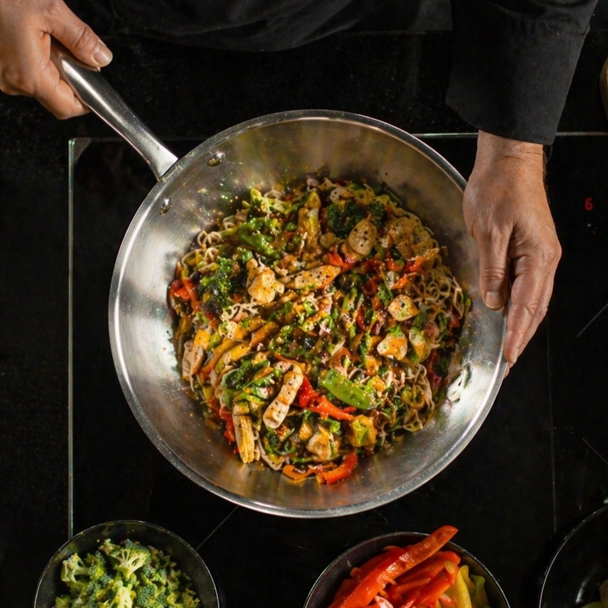 Wok Triply 28cm en inox lors d'une cuisson de nouilles sautées aux légumes et crevettes, vue du dessus