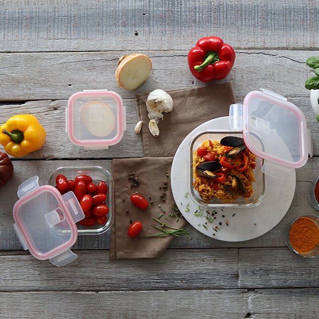 Vue aérienne boîtes hermétiques carrées Clémentine avec couvercles roses, contenant tomates cerises et plat cuisiné sur table en bois avec légumes frais