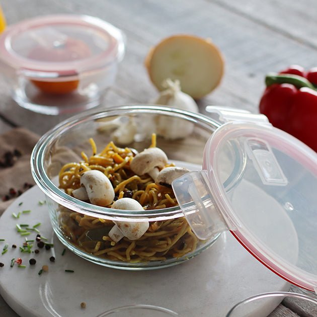Boîte hermétique ronde 930ml en verre avec couvercle transparent, remplie de pâtes et champignons, vue en situation sur plan de travail