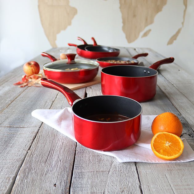 Set de casseroles Cerise rouges en aluminium avec revêtement antiadhésif, disposées sur table en bois rustique