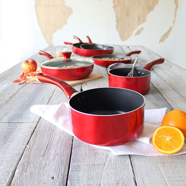 Collection de casseroles Cerise rouges en aluminium antiadhésif, vue d'ensemble avec couvercles et accessoires sur table bois