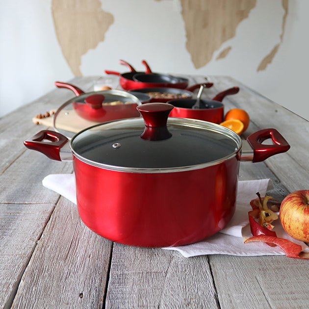Faitout Cerise rouge 24 cm en aluminium avec couvercle en verre, présenté sur table en bois avec autres ustensiles